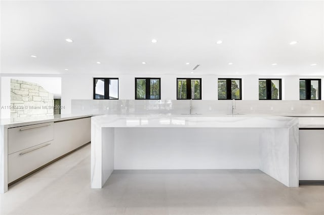 kitchen featuring white cabinetry, light stone countertops, sink, and tasteful backsplash