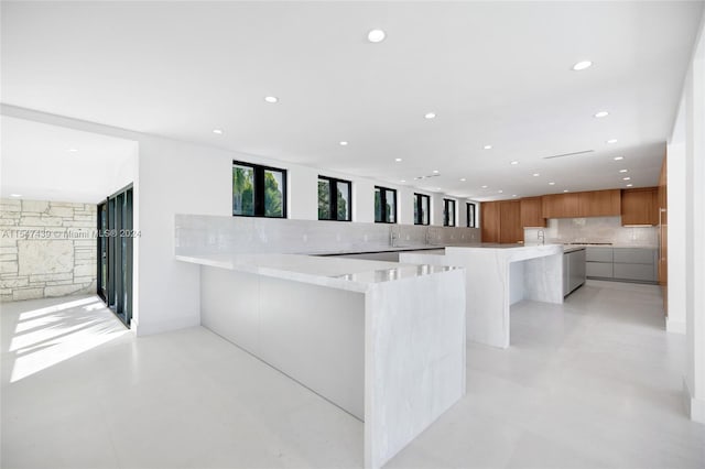 kitchen with backsplash, light stone counters, and kitchen peninsula