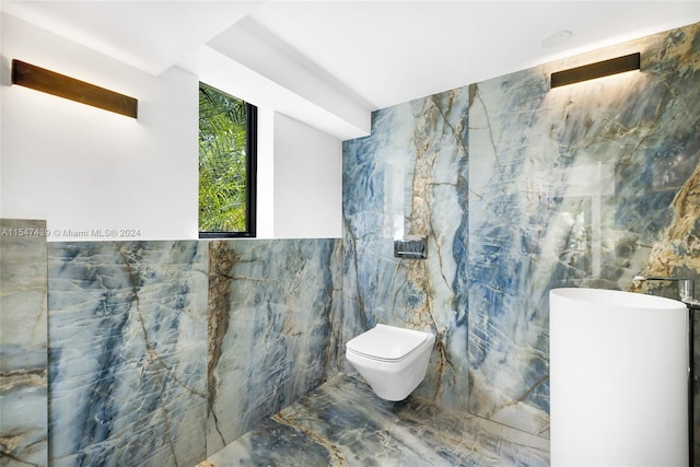 bathroom with toilet and tile walls