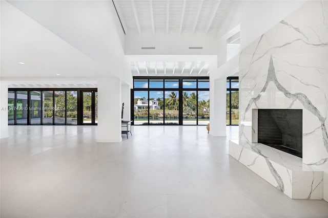 unfurnished living room with a high ceiling, concrete flooring, and a high end fireplace