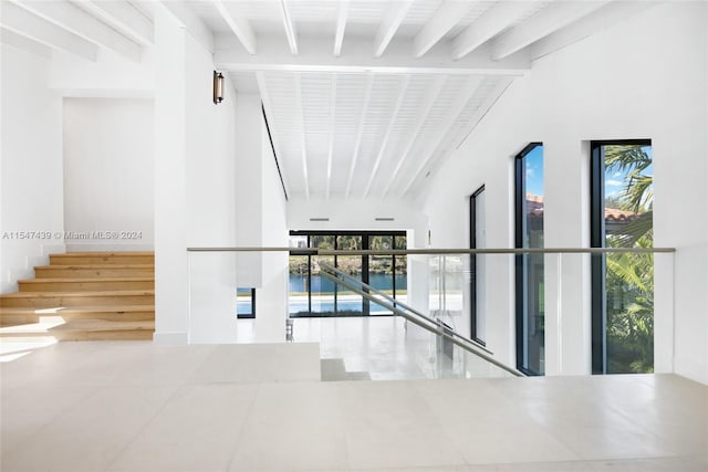 hallway with plenty of natural light, beam ceiling, and tile floors