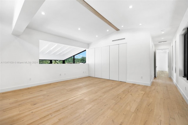 spare room with vaulted ceiling with beams and light hardwood / wood-style flooring