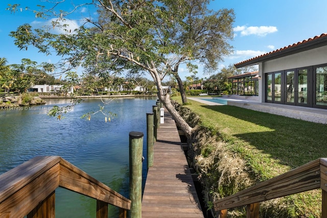 view of dock with a water view and a yard