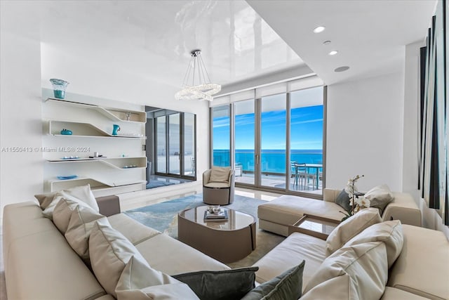 living room with a water view, a notable chandelier, hardwood / wood-style flooring, and a wall of windows