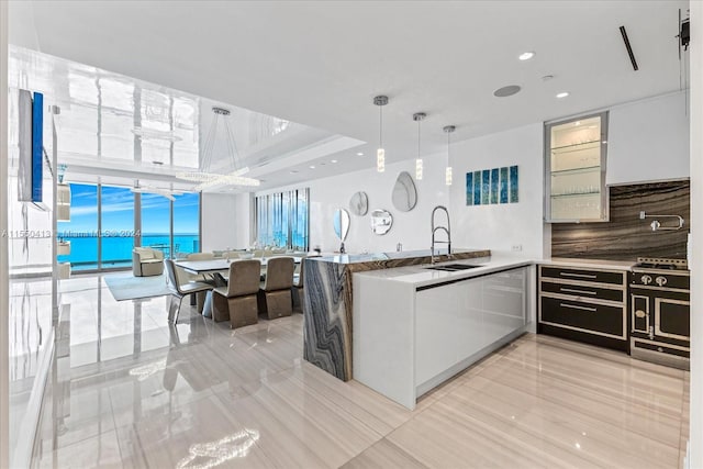 kitchen with decorative light fixtures, light tile floors, a wall of windows, backsplash, and sink