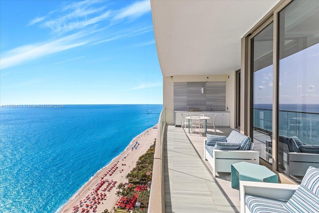 balcony with a water view, a beach view, and an outdoor living space