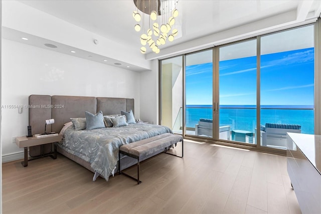 bedroom with a chandelier, a water view, access to exterior, and light wood-type flooring