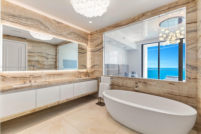 bathroom featuring a bath to relax in, tile floors, vanity, and an inviting chandelier