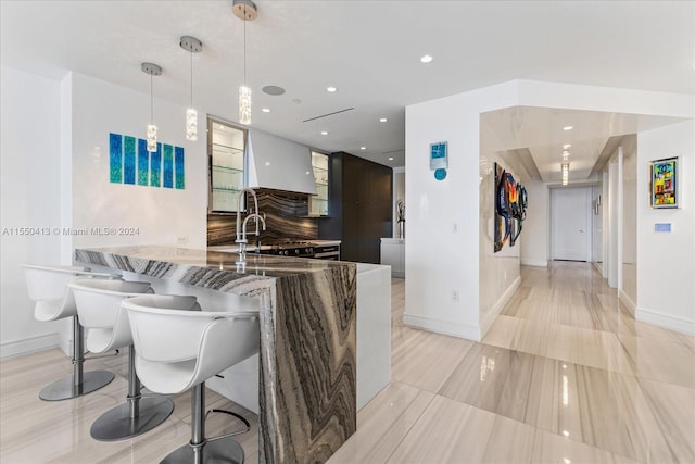 kitchen featuring kitchen peninsula, sink, a breakfast bar, light tile flooring, and decorative light fixtures