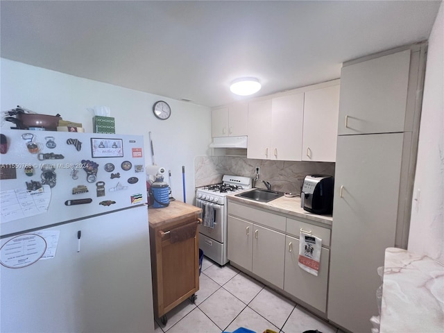 kitchen featuring sink, white refrigerator, range with gas stovetop, backsplash, and white cabinetry