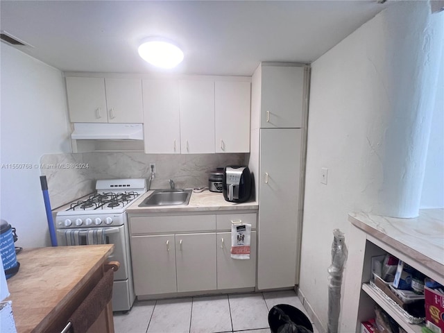 kitchen with backsplash, sink, light tile floors, white cabinets, and double oven range