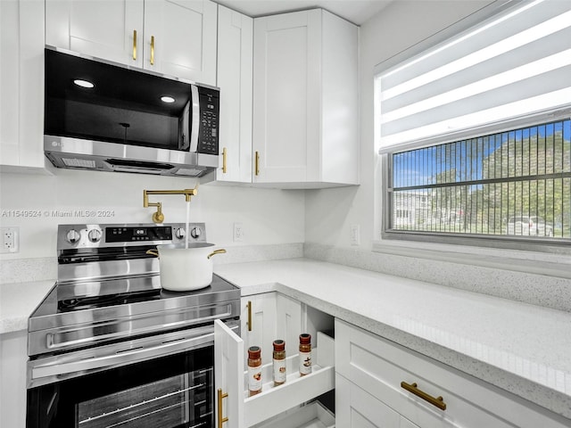 kitchen featuring plenty of natural light, appliances with stainless steel finishes, and white cabinetry