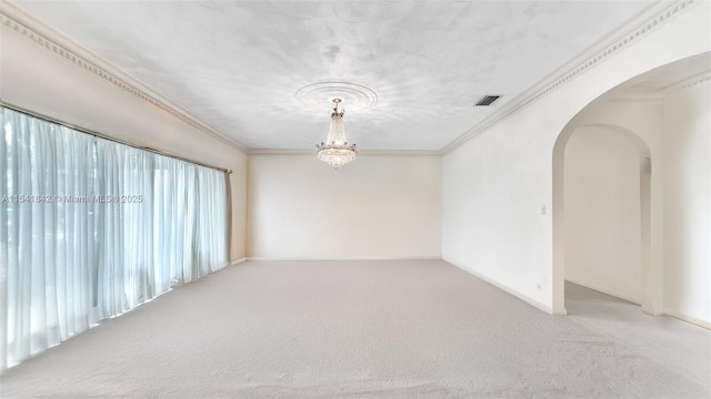 carpeted empty room featuring a chandelier and ornamental molding