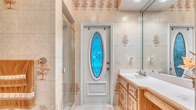 bathroom with vanity, a shower with shower door, and tile walls