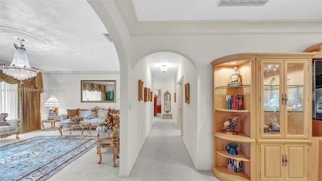 hallway featuring crown molding, an inviting chandelier, and light carpet