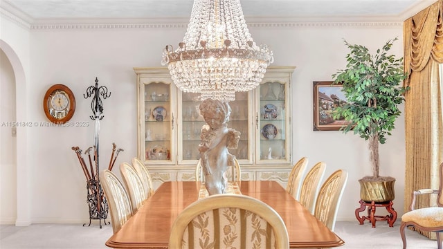 carpeted dining room featuring an inviting chandelier and ornamental molding