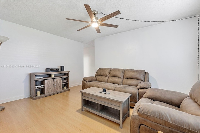 living room featuring ceiling fan, a textured ceiling, and light wood-type flooring