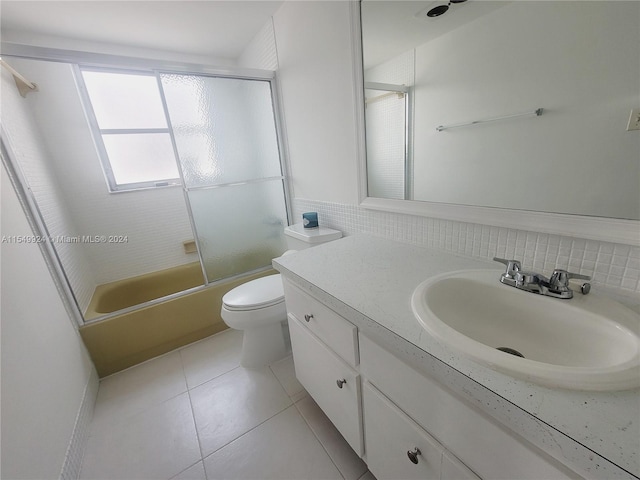 full bathroom with tile floors, combined bath / shower with glass door, backsplash, toilet, and vanity with extensive cabinet space