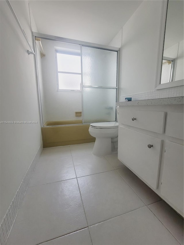 full bathroom with toilet, tile floors, vanity, and enclosed tub / shower combo