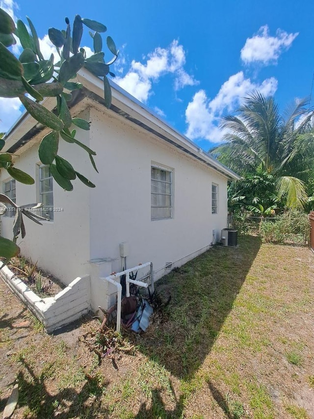 view of side of home with a lawn and cooling unit