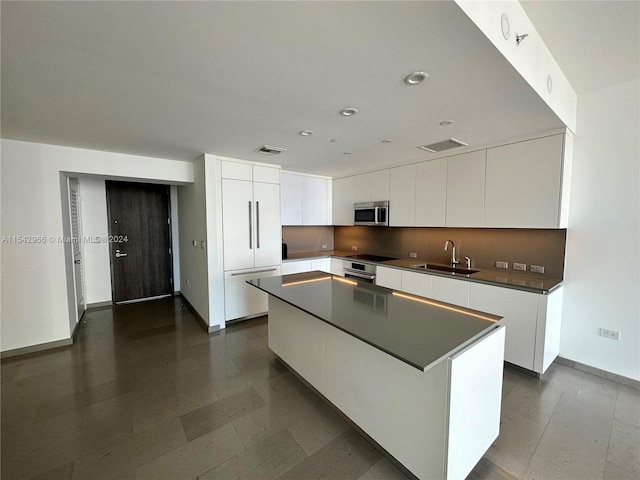 kitchen featuring white cabinets, a center island, and sink