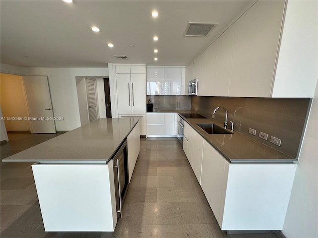 kitchen with a kitchen island, tasteful backsplash, white cabinets, and sink