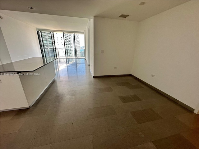 tiled empty room featuring a wall of windows