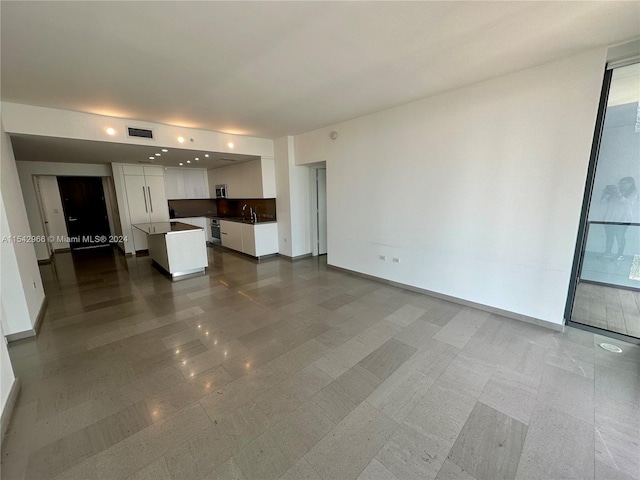 unfurnished living room featuring light tile floors and sink