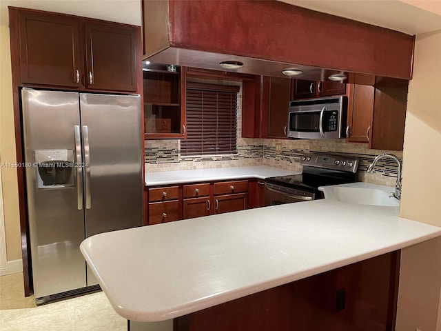 kitchen featuring sink, tasteful backsplash, kitchen peninsula, light tile patterned floors, and appliances with stainless steel finishes