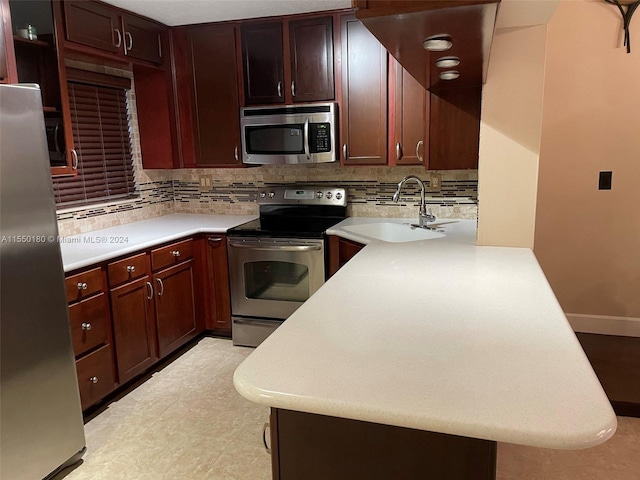 kitchen with tasteful backsplash, kitchen peninsula, sink, and stainless steel appliances