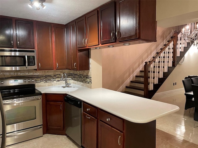 kitchen with kitchen peninsula, appliances with stainless steel finishes, tasteful backsplash, sink, and light tile patterned flooring