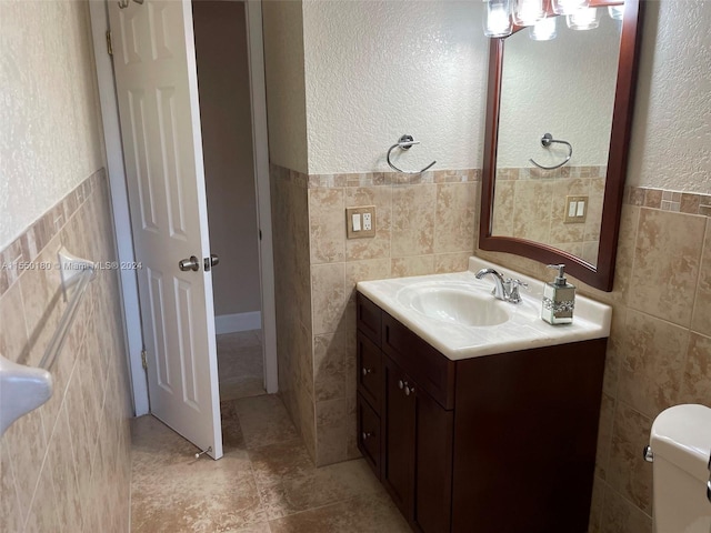 bathroom with vanity, toilet, and tile walls