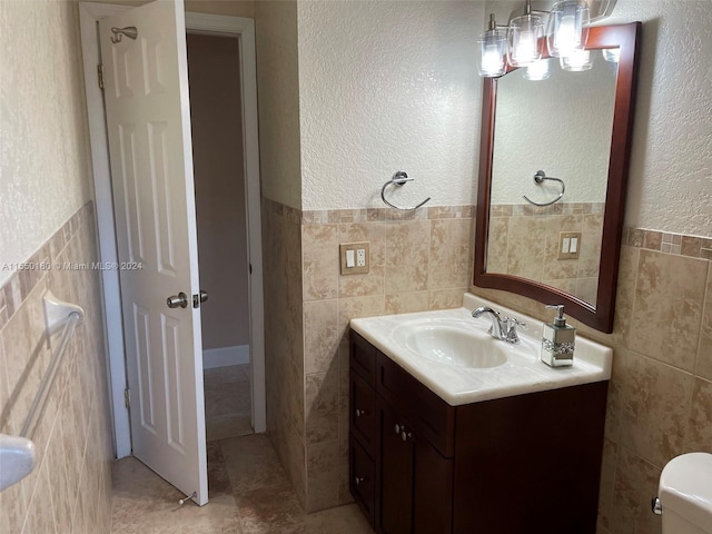 bathroom with vanity, tile walls, and toilet