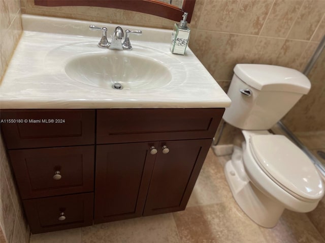 bathroom with vanity, toilet, and tile walls