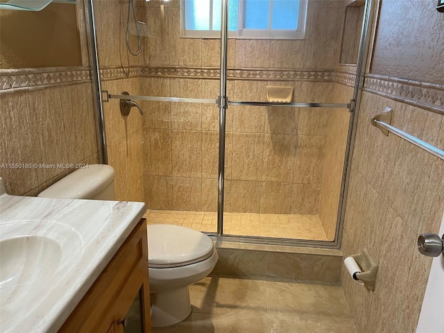 bathroom with tile patterned floors, vanity, toilet, and an enclosed shower