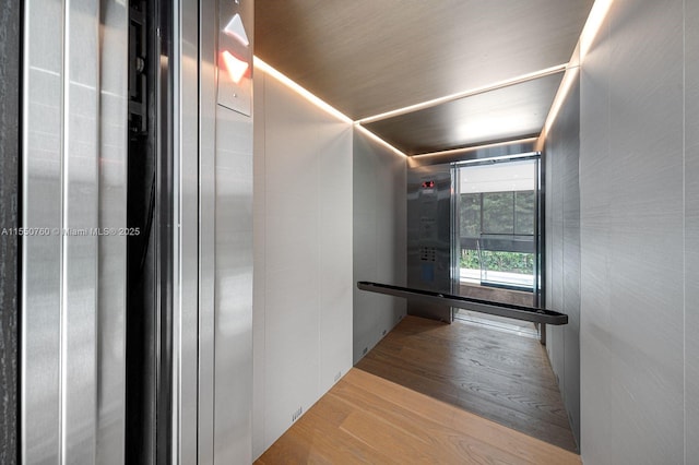 hallway with light wood-type flooring and elevator