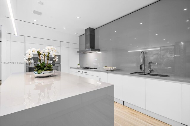 kitchen with gas stovetop, backsplash, white cabinetry, modern cabinets, and wall chimney exhaust hood