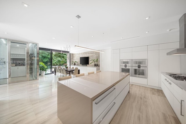 kitchen with white cabinets, hanging light fixtures, a large island, and modern cabinets