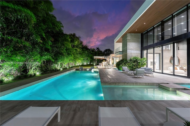 pool at dusk with an outdoor pool and an outdoor living space