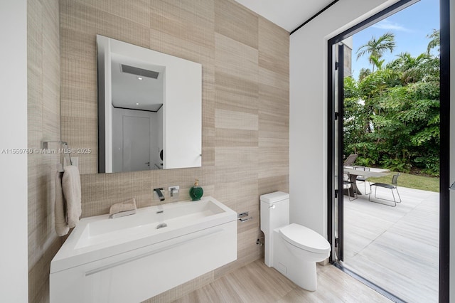 bathroom with vanity, toilet, and tile walls