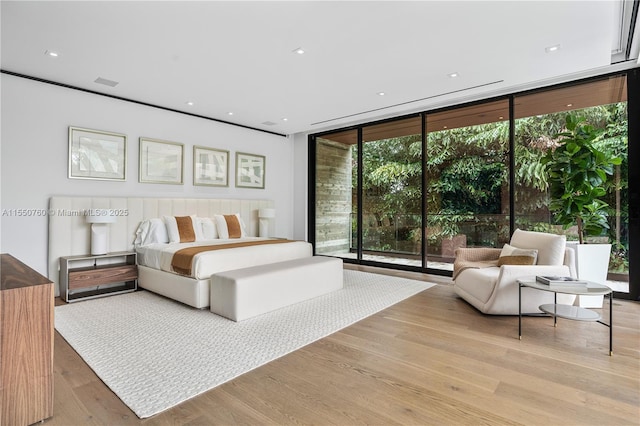 bedroom featuring light wood-style floors, visible vents, and floor to ceiling windows