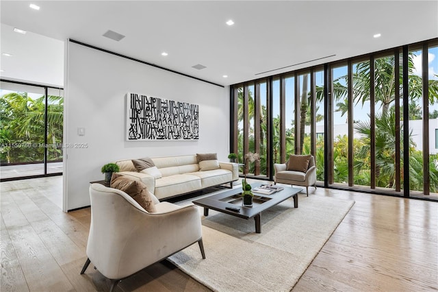 living area with expansive windows, light wood finished floors, and recessed lighting