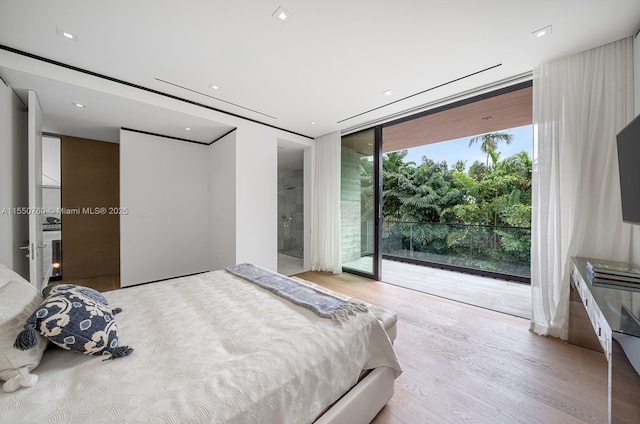 bedroom featuring access to exterior, light wood-style flooring, and a wall of windows