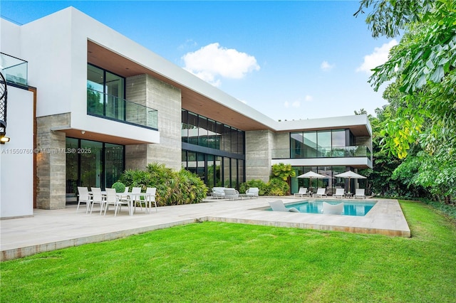 rear view of house with a patio, a lawn, and an outdoor pool