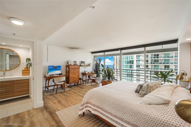 bedroom with floor to ceiling windows, sink, and light hardwood / wood-style floors