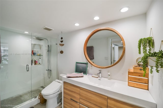 bathroom featuring toilet, vanity, and a shower with door