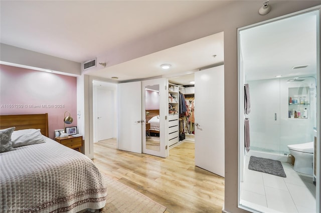 bedroom featuring a closet, light wood-type flooring, and ensuite bathroom