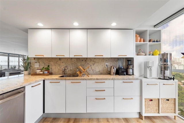 kitchen featuring white cabinetry, sink, light stone counters, light wood-type flooring, and dishwasher