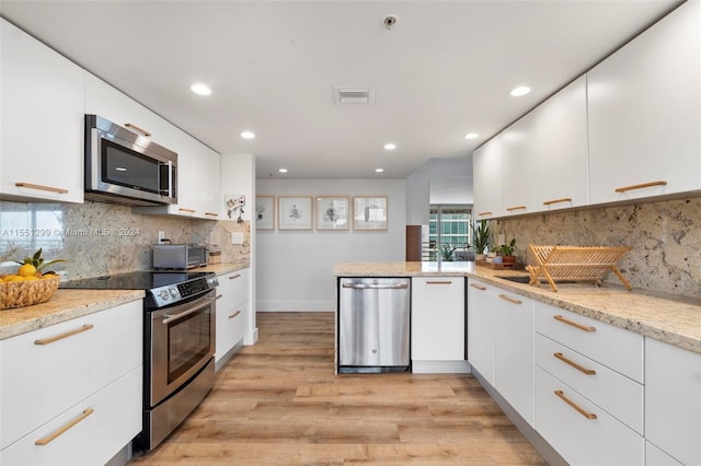 kitchen with white cabinetry, appliances with stainless steel finishes, light stone counters, and light wood-type flooring