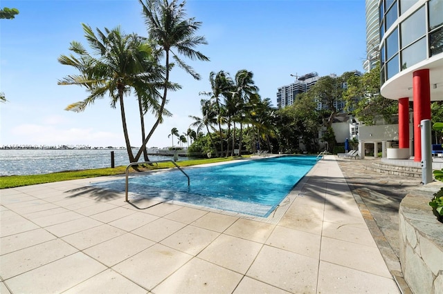 view of pool featuring a water view and a patio